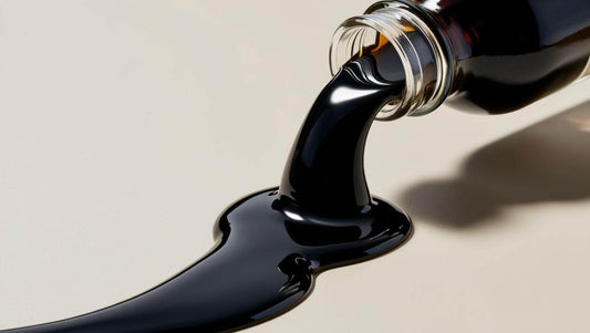 Black resin pouring from a glass bottle, illustrating natural supplement features of Shilajit.